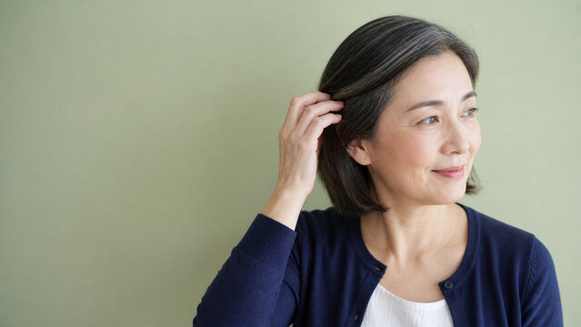 ヘアケア 髪に触れる日本人女性 50代と余白のある背景