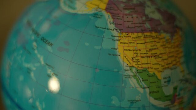 Close-up of globe rotating slowly. Pacific Ocean labeled in clear text. North America visible with distinct borders. Globe shows continents and oceans with color-coded regions. Ideal for educational