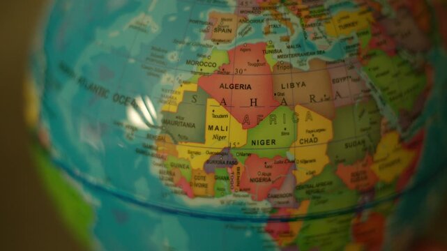 Globe spins slowly, showing colorful world map. Atlantic Ocean and Africa are clearly visible. Soft light glints off globe's surface. Ideal for travel or education themes. No people or animals present