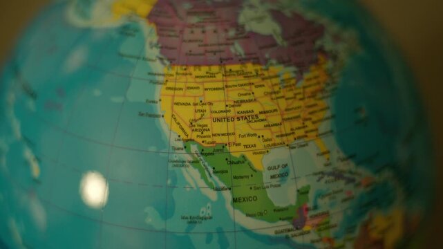 Globe rotates slowly, showing continents and oceans. Bright lights reflect off its polished surface. North America appears vividly colored and clearly marked.