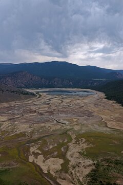 Aerial view of Clear Creek Reservoir with low water levels exposing the lake bed surrounded by mountains and pine forests in Chaffee County, Colorado, United States.