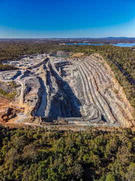 Aerial view of the Holcim Australia - Petrie Quarry, showing deep terraced excavation pits and surrounding dense eucalyptus forest, Kurwongbah, Queensland, Australia.