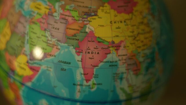 Close-up globe rotates, highlighting India and surrounding regions. Soft focus adds depth to the map's colorful countries. Globe spins gently, showcasing global geography from a single vantage point
