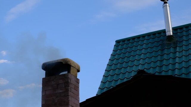 House roof with brick chimney emitting dense smoke, cottage house in the forest. Travelling and vacations, rural scene