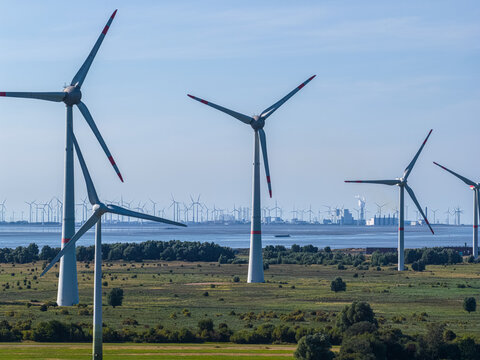 Aerial view of wind turbines in a field near the Volkswagenwerk Emden factory with industrial buildings in the background in Emden, Niedersachsen, Germany.