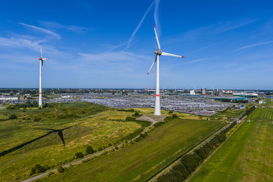 Aerial view of the Volkswagenwerk Emden factory with wind turbines, rows of parked cars, and green fields in Emden, Niedersachsen, Germany.