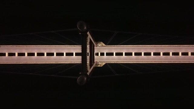 Top-down aerial night view of the illuminated 1915 &Ccedil;anakkale Bridge crossing the Dardanelles Strait in Turkey, showing the massive suspension bridge deck, empty highway lanes and dark sea below.