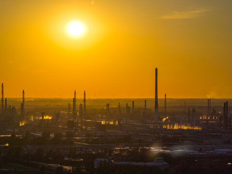 Aerial view of the PKN Orlen refinery complex at sunset, featuring industrial chimneys and glowing golden light over the facility in Plock, Masovian Voivodeship, Poland.