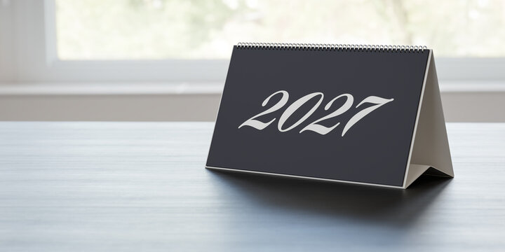 A desk calendar on an office desk showing the year 2027 on the cover sheet. New year concept. Selective focus