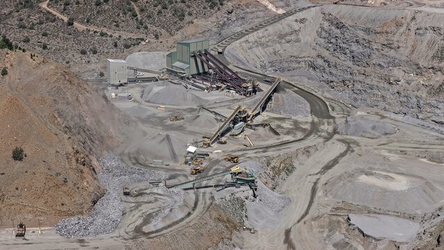 Aerial view of the open-pit mining operation at Floyd Hill featuring industrial processing plants, conveyor belts, piles of crushed rock, and heavy machinery in Floyd Hill, Colorado, United States.