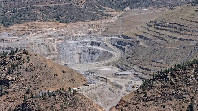 Aerial view of the open-pit mine at Floyd Hill, featuring terraced excavation, rocky terrain, and winding access roads set within the mountainous landscape of Floyd Hill, Colorado, United States.