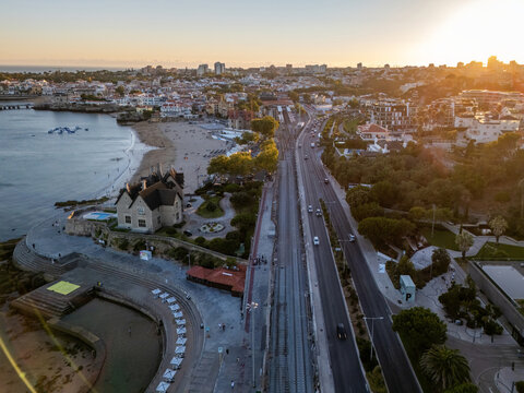 Aerial view of Avenida Marginal running alongside the railway tracks and the sandy beach in Cascais, Lisboa, Portugal.