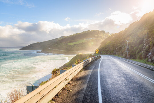 Empty stretch of the Great Ocean Road on the south-eastern coast of Australia at sunset in autumn. Mist coming form the ocean hangs over the road. Lens flare. 