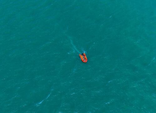 Aerial view of a small orange inflatable boat navigating the turquoise waters of the Port de Boulogne-sur-Mer, Boulogne-sur-Mer, Hauts-de-France, France.