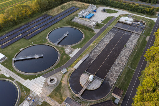 Aerial view of the RWZI - Beemster wastewater treatment plant with circular sedimentation tanks and rectangular aeration basins in Zuidoostbeemster, Noord-Holland, Netherlands.