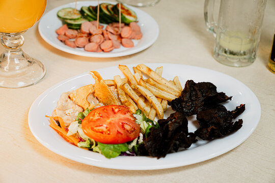 Cecina with fries and salad in a plate over the table