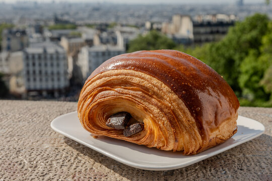 French pastry roll pain au chocolat for traditional breakfast, fresh baked in artinasal bakery in Paris, France, view from Montmartre and Basilica Sacre-Coeur to central Paris