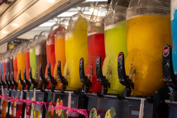 Colorful fresh fruit granita ice cold juices in glass dispensers behind  cafe counter, with citrus and mixed flavors ready for refreshing drinks © barmalini