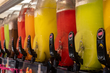 Colorful fresh fruit granita ice cold juices in glass dispensers behind  cafe counter, with citrus and mixed flavors ready for refreshing drinks © barmalini