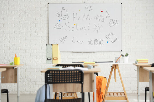 Empty classroom with whiteboard displaying "hello school" and educational drawings, ready for students to learn