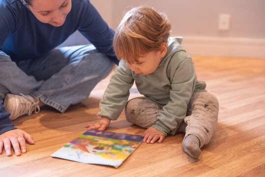 A 23-month-old toddler boy and his mother looking together at the same picture