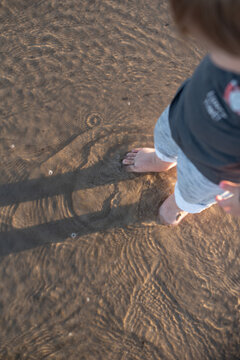 Baby boy standing in the shallow water
