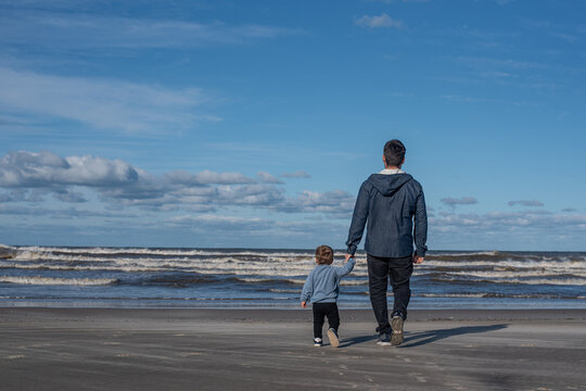 Father and Child Holding Hands on Beach