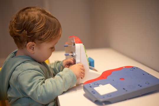 A curious toddler examining the internal wires of a broken cash register with the cover open