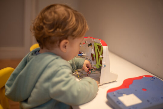 A curious toddler examining the internal wires of a broken cash register with the cover open