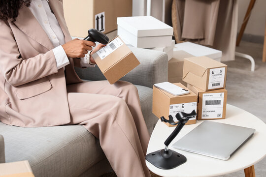Woman scanning a shipping label on a cardboard box with a barcode reader for inventory management and logistics