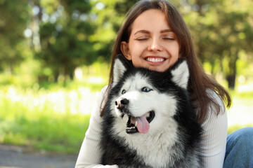 Happy young woman with closed eyes embracing her siberian husky dog outdoors in a park, Strong bond and affection between a pet owner and her companion animal © Pixel-Shot