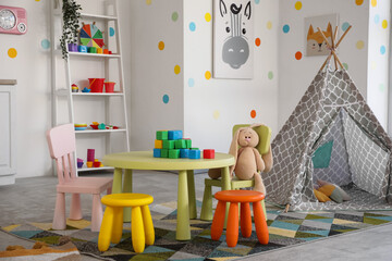 Interior of stylish playroom with toys, table and play tent in kindergarten © Pixel-Shot