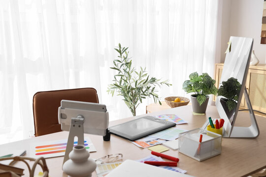 Graphic designers workplace with tablet and color palettes in office