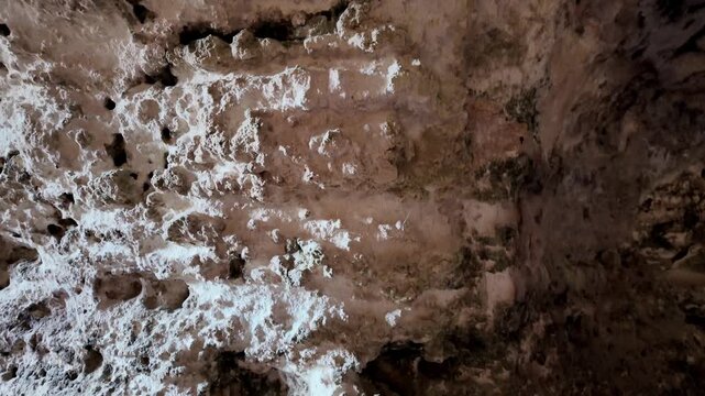 Malta, Xemxija Heritage trail, Punic caves. Ancient cave walls show signs of erosion and time. White powdery residue contrasts with darkened stone. Weathered textures reveal hidden history and mystery