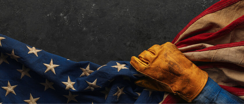 Work glove pulling the American flag with worn black background. Symbolic of hard working blue collar workers, pride in American manufacturing or products Made in USA, or to celebrate US Labor Day.