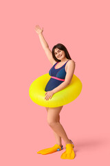 Beautiful young woman in swimsuit and flippers with inflatable ring on pink background © Pixel-Shot
