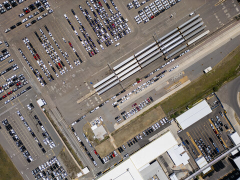 Aerial view of a car factory with rows of new vehicles parked in a large lot and train cars loaded with automobiles San Luis Potosi, San Luis Potosi, Mexico.