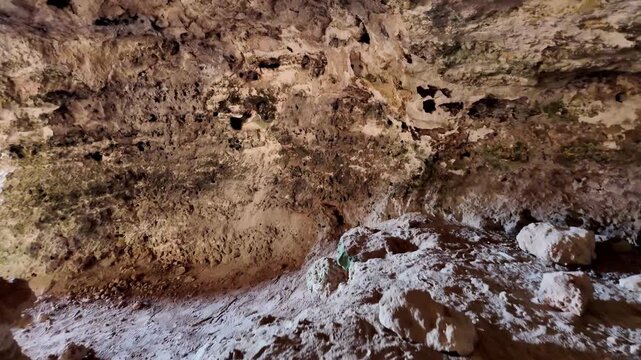 Ancient stone walls line cave interior. Earthen floor shows signs of age and use. Rugged walls reveal natural erosion patterns. This site hints at ancient human habitation. Ideal for historical