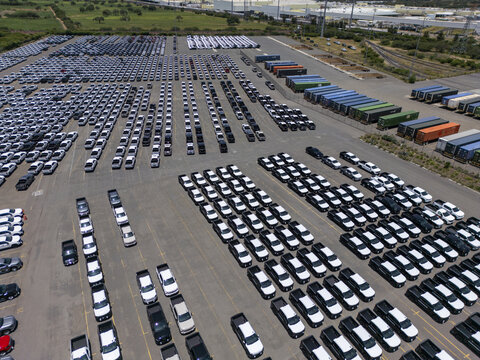 Aerial view of a car factory parking lot filled with rows of new pickup trucks and shipping containers in San Luis Potosi, San Luis Potosi, Mexico.