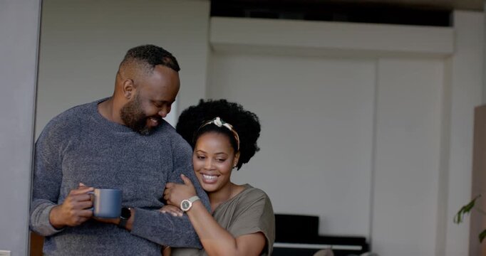 African American couple standing in doorway linking arms, man sipping mug, each sip drawing smiles