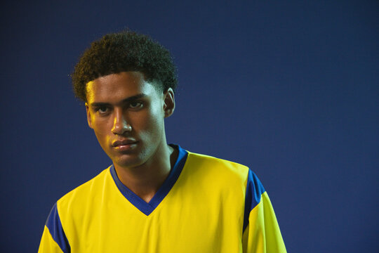 African American man posing in studio, wearing yellow sports jersey with blue trim