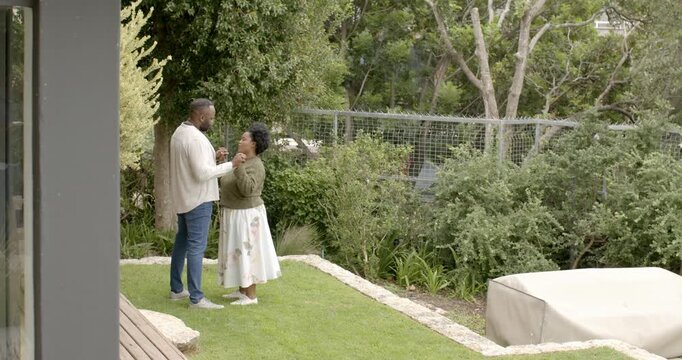 African couple standing yard, man proposing with ring while holding hands, embracing, copy space