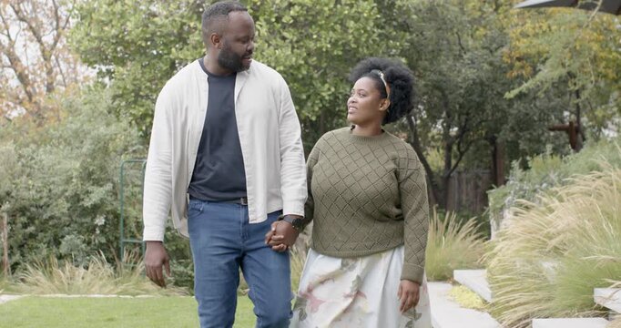 African American couple holding hands walking along steps in backyard, linking arms sharing joy