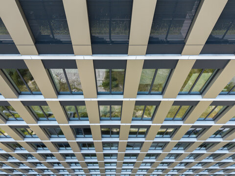Aerial view of the repetitive geometric facade of a modern office building with rows of windows and beige structural panels in Poland.