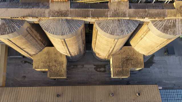 Aerial view of industrial cement and concrete plant silos with textured metal roofs and concrete walls in Poland.