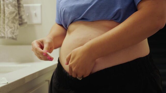 Woman giving herself auto-injector injection in abdomen for biologic allergy therapy, GLP-1 weight loss medication, or chronic medical treatment