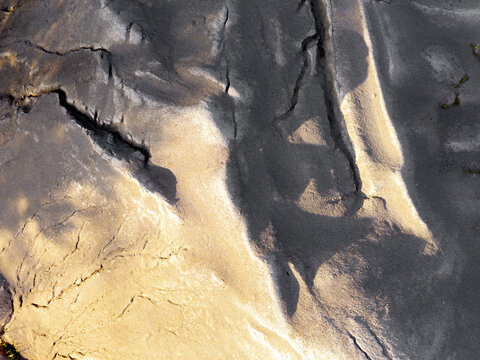 Aerial view of sandy terrain with intricate textures, natural cracks, and soft shadows cast across the dunes in Poland.