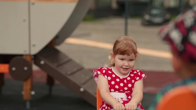 Girl plays on playground equipment in city park during afternoon