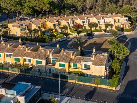 Aerial view of Quinta da Marinha featuring yellow residential townhouses with terracotta roofs, green shutters, manicured hedges, and paved streets in Cascais, Lisbon, Portugal.