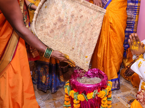 Traditional Indian Hindu Wedding Ritual Pouring Sacred Rice from a woven bamboo winnowing basket (chaat, suupa)